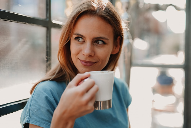 Photo of woman drinking a hot cup of coffee with her favorite creamer.