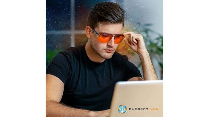 Photo of man protecting his eyes from blue light while working on his computer