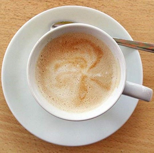 Photo of coffee in a cup with creamer.
